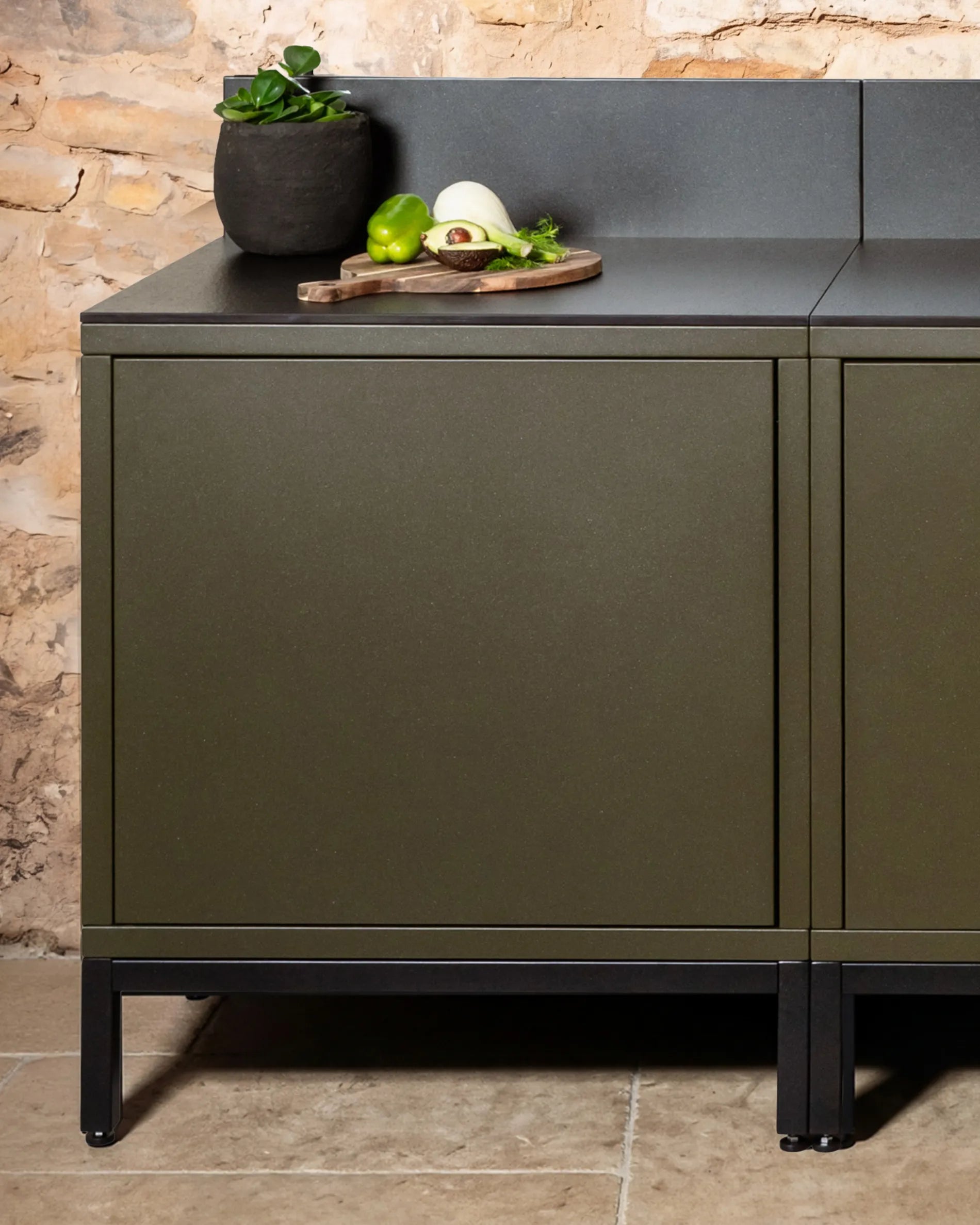 Struttura bassa nera PILOTIS sotto moduli verde oliva, cucina da esterno con piano di lavoro nero