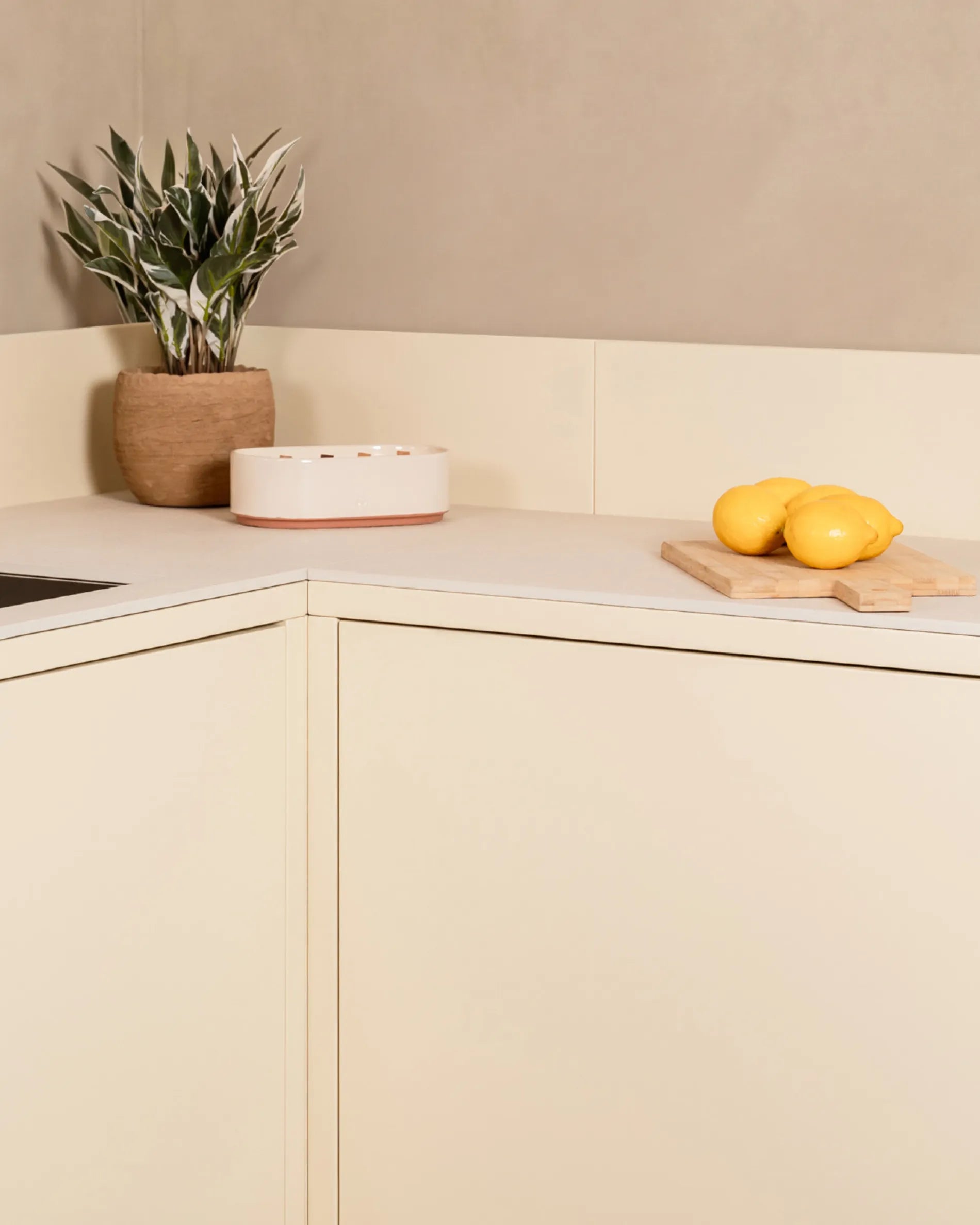 Modulo angolare beige crema PILOTIS per cucina esterna, con pianta e limoni su tagliere