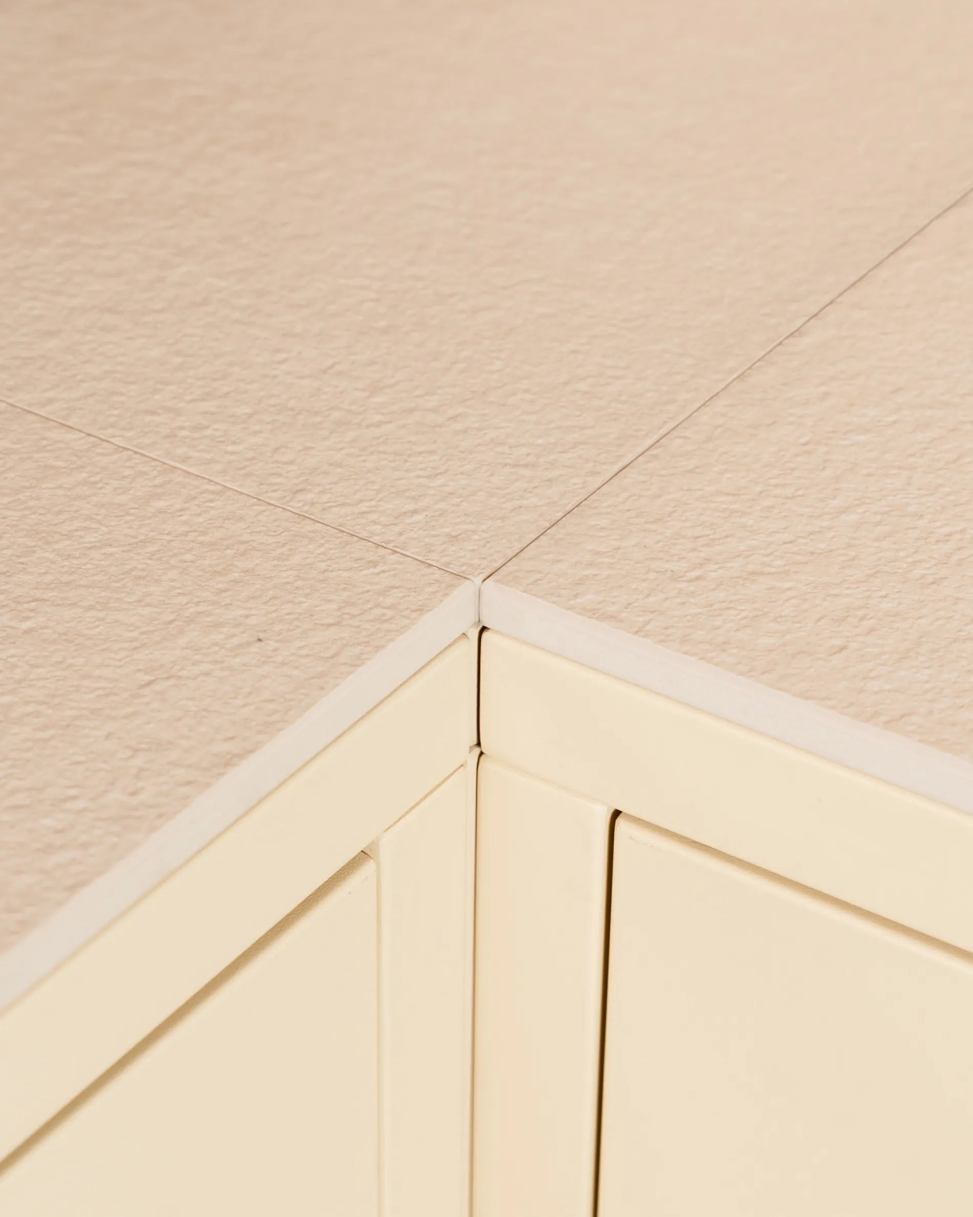 Dettaglio dell’angolo del piano beige crema PILOTIS, primo piano sul taglio della cassa