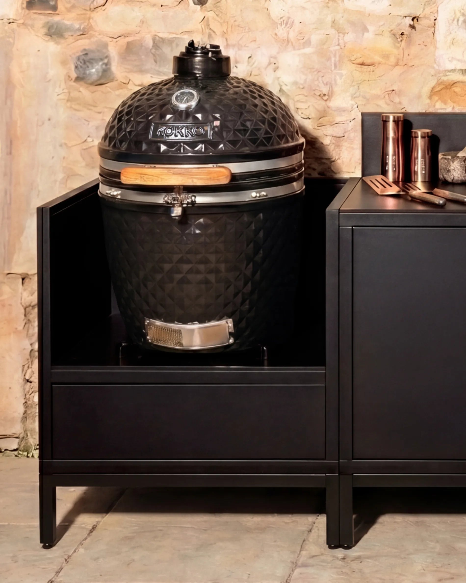 Kamado nero Kokko installato nel mobile PILOTIS con accessori in rame, cucina da esterno