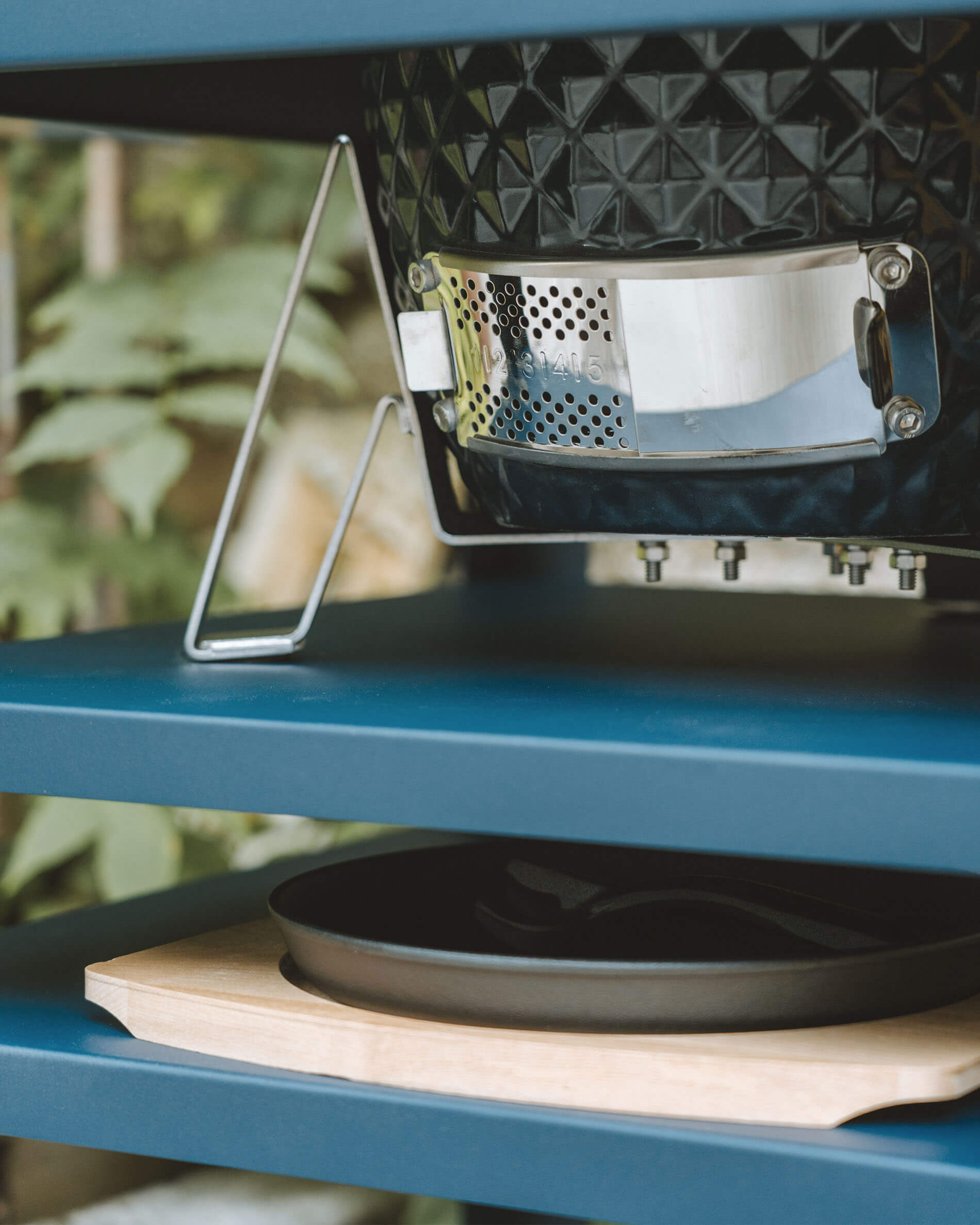 Primo piano sulla ventilazione inferiore in acciaio inox di un kamado Kokko, integrata in un carrello metallico con cassetto raccogli-cenere.