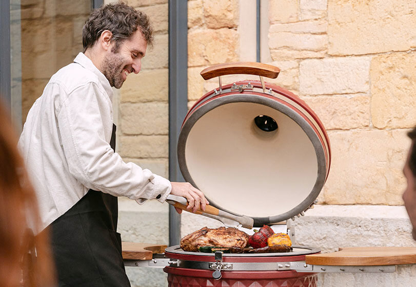 Esperto Kokko che utilizza un kamado rosso ossido all’aperto per mostrare le migliori pratiche di cottura.