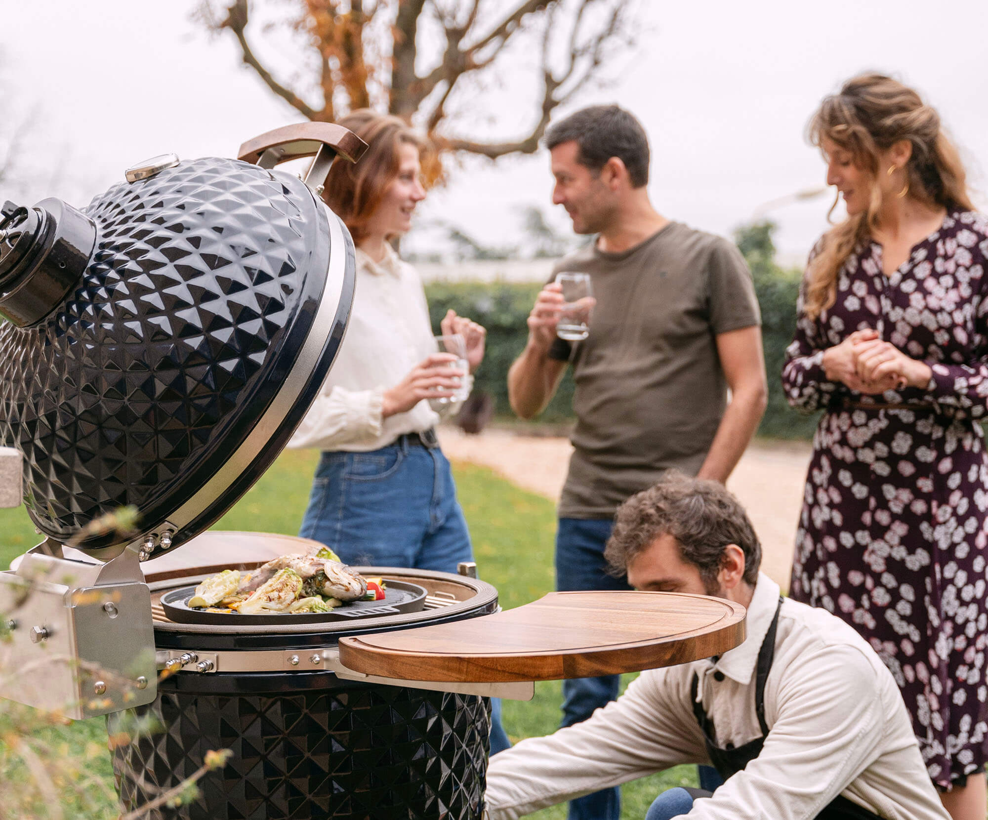 Kamado Kokko nuova edizione in uso, con cibi in cottura per illustrare convivialità e prestazioni del barbecue.