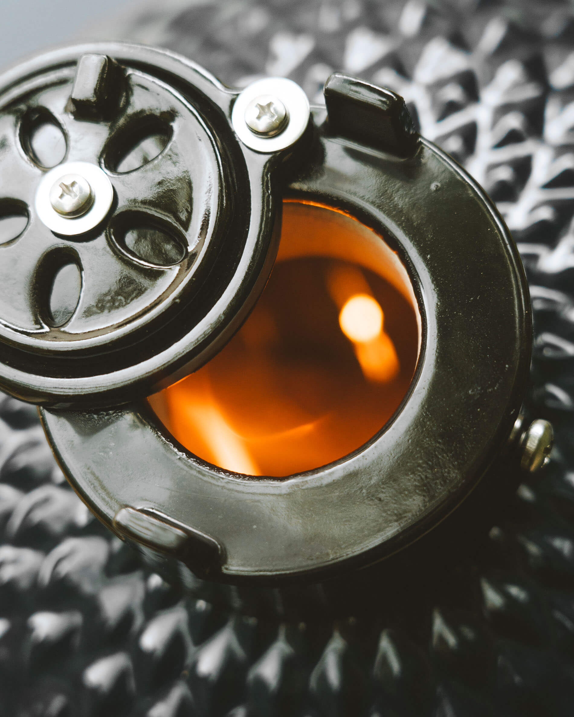 Vista ravvicinata del sistema di ventilazione superiore di un kamado Kokko, con apertura circolare e braciere incandescente visibile.