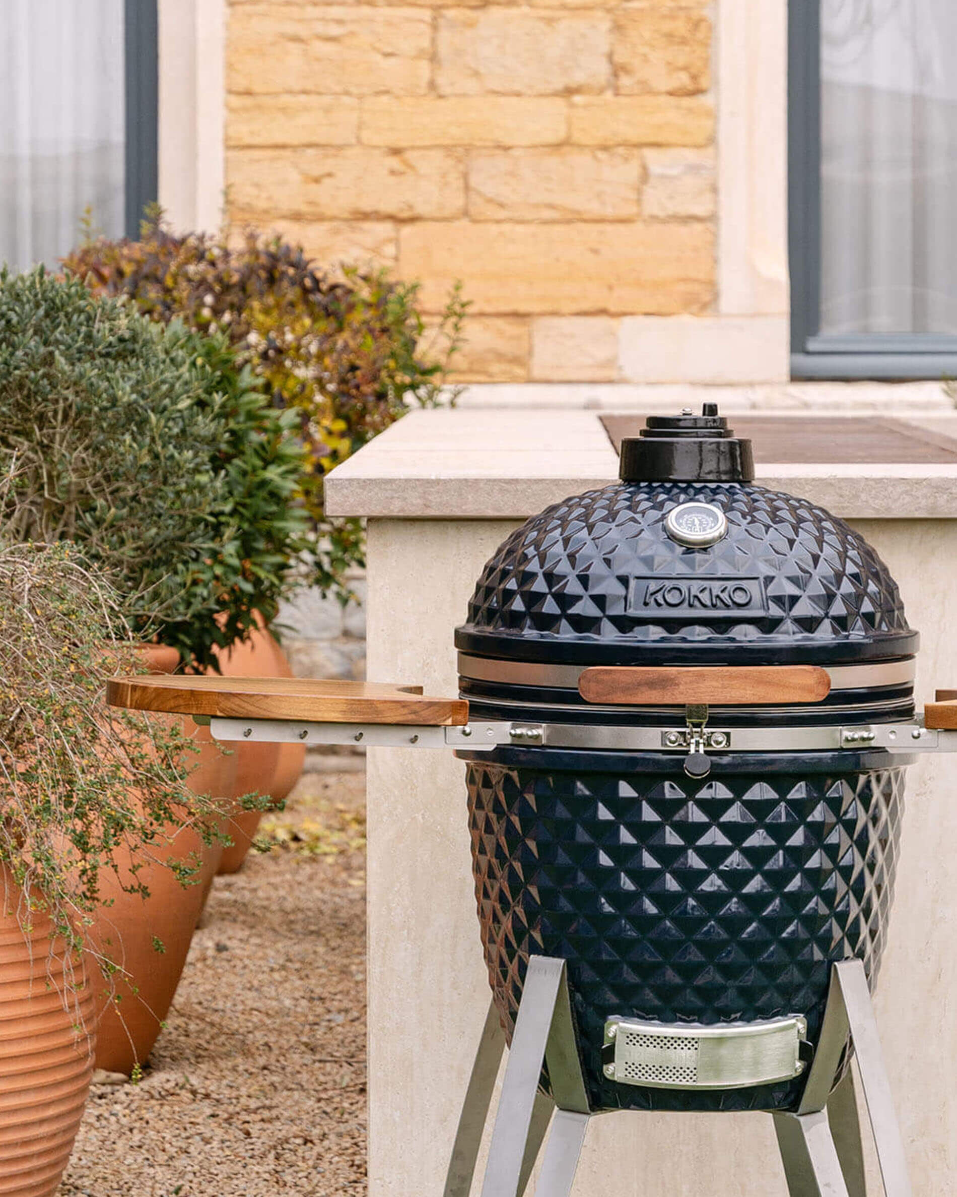 Kamado Kokko 22 pollici colore navy, presentato da solo all’esterno.