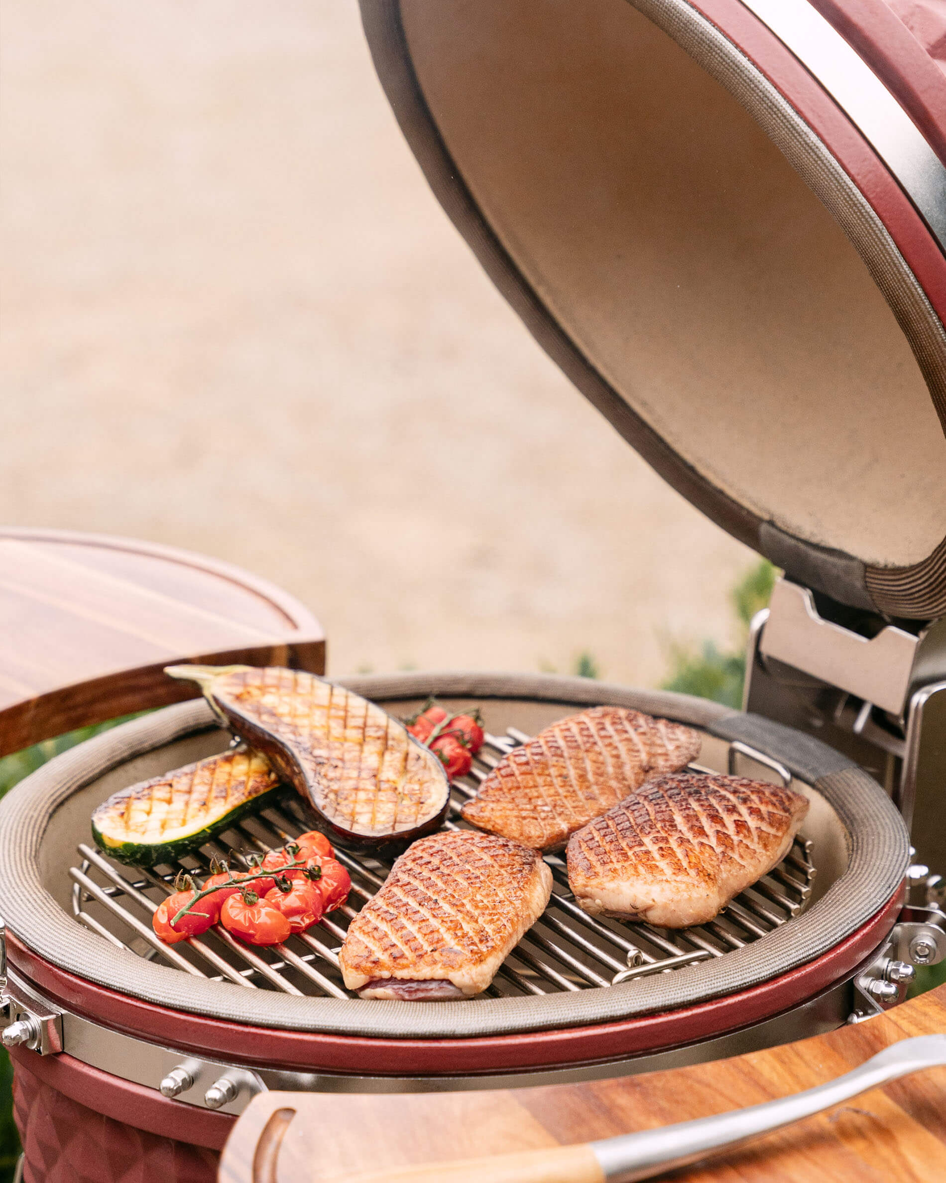Kamado Kokko L 18 pollici durante la cottura con carne e verdure sulla griglia.