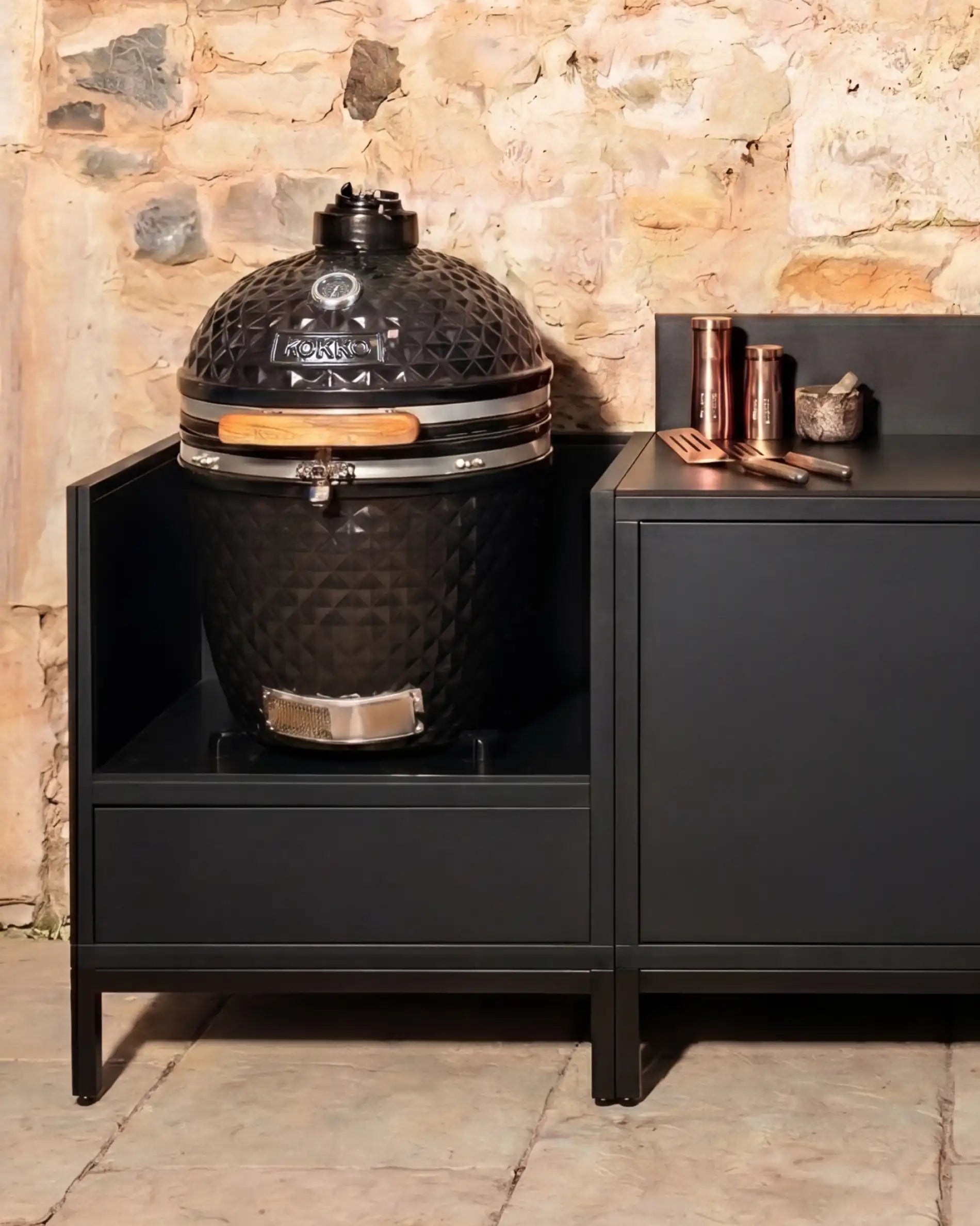 Kamado Kokko nero integrato in una cucina esterna con vani portaoggetti