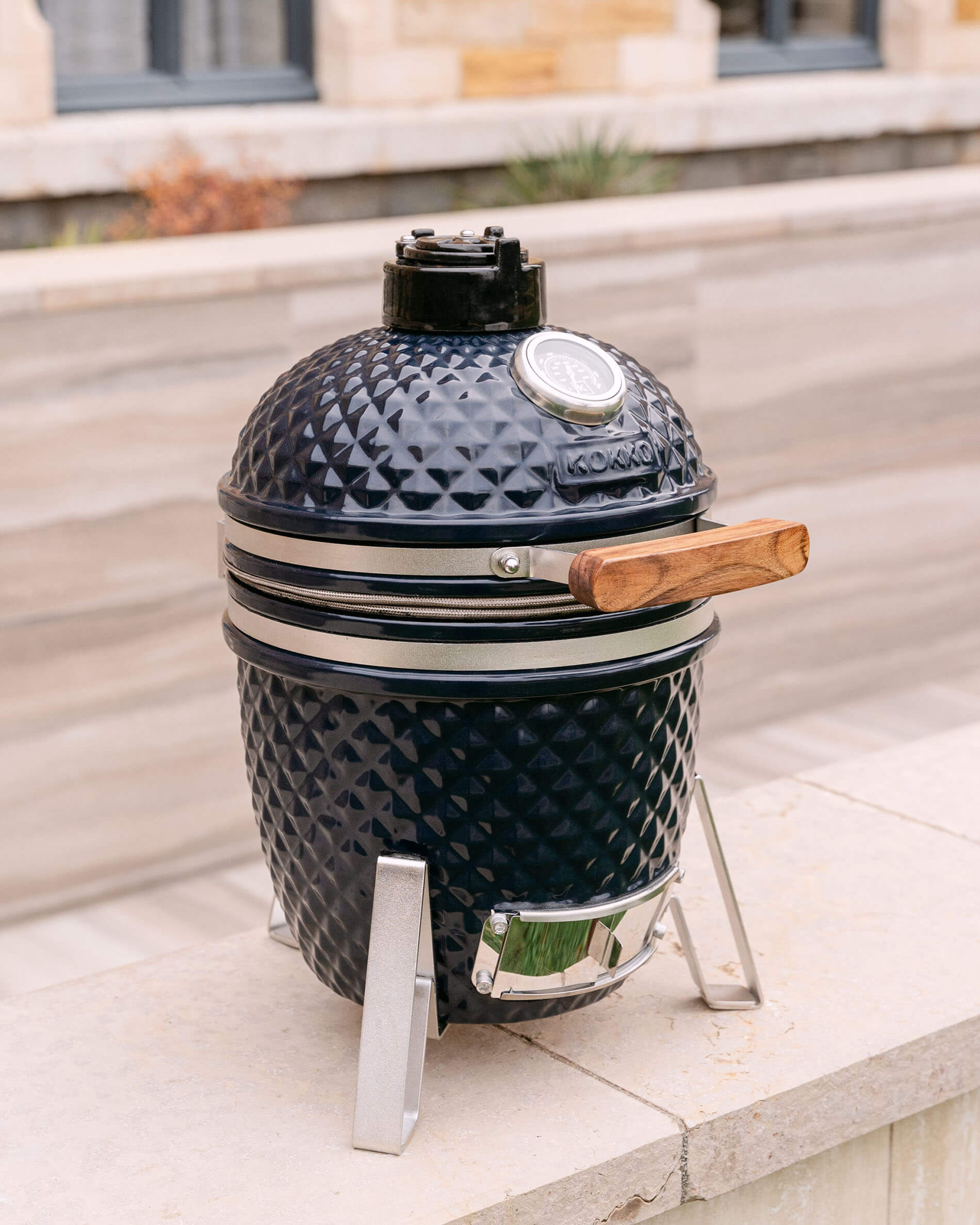 Kamado Little Kokko 13 blu navy esposto sul suo supporto all’aperto.