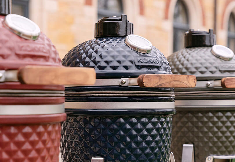Allineamento di kamado Kokko di diversi modelli e colori, esposti fianco a fianco all’aperto.
