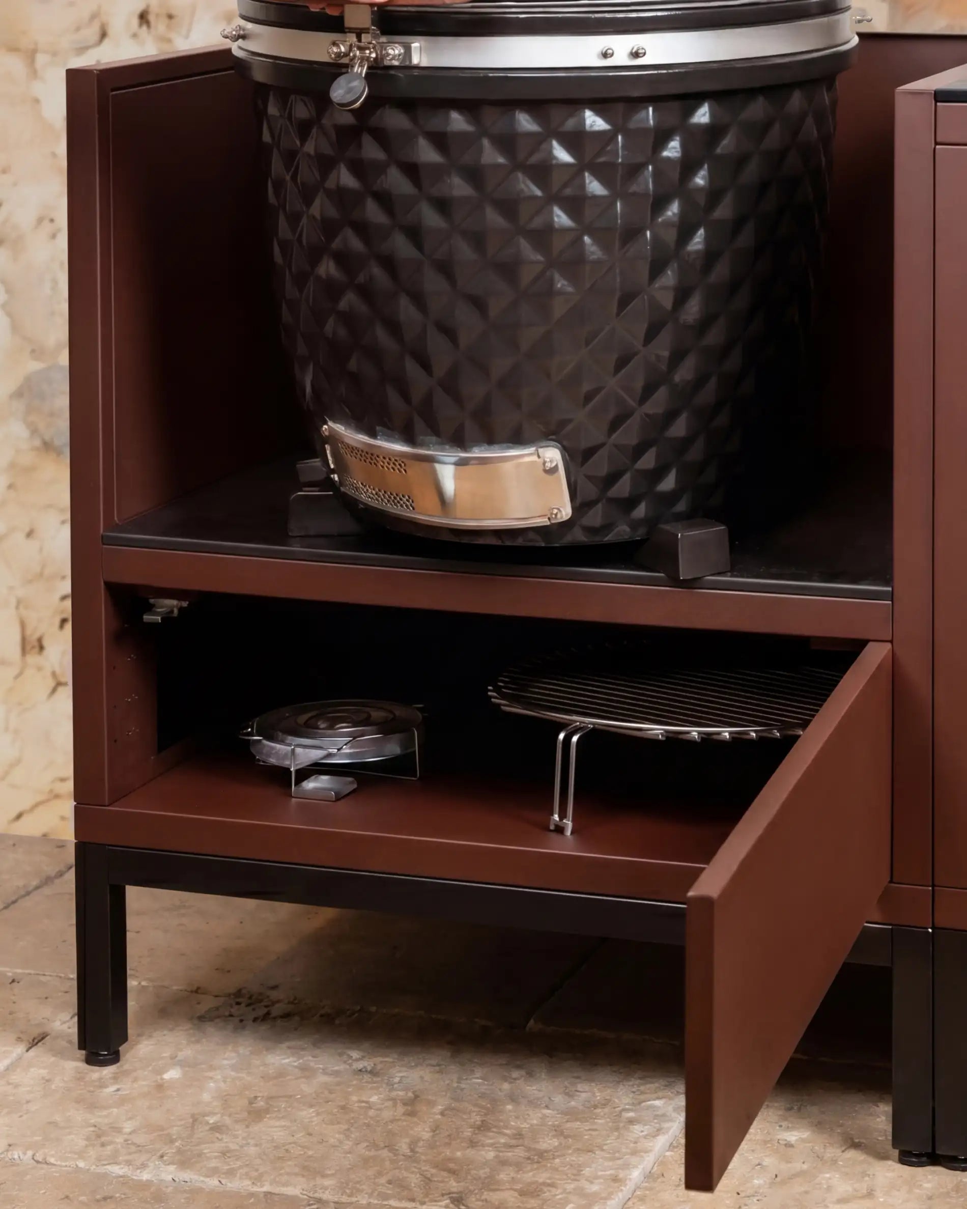 Kamado Kokko nero integrato in un modulo rust con mensola portaoggetti aperta e accessori da cottura