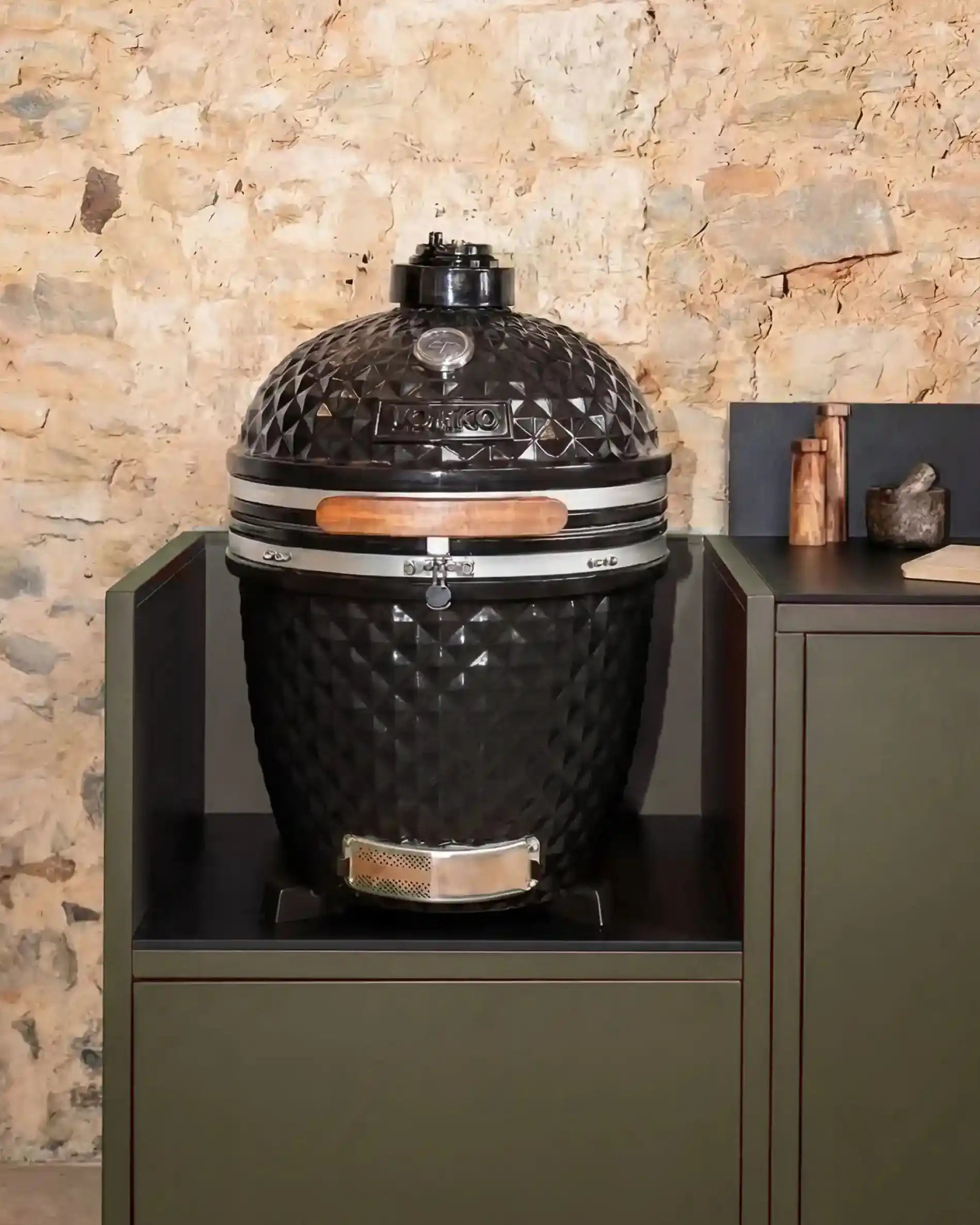 Kamado Kokko nero integrato su modulo olive con piano di lavoro nero