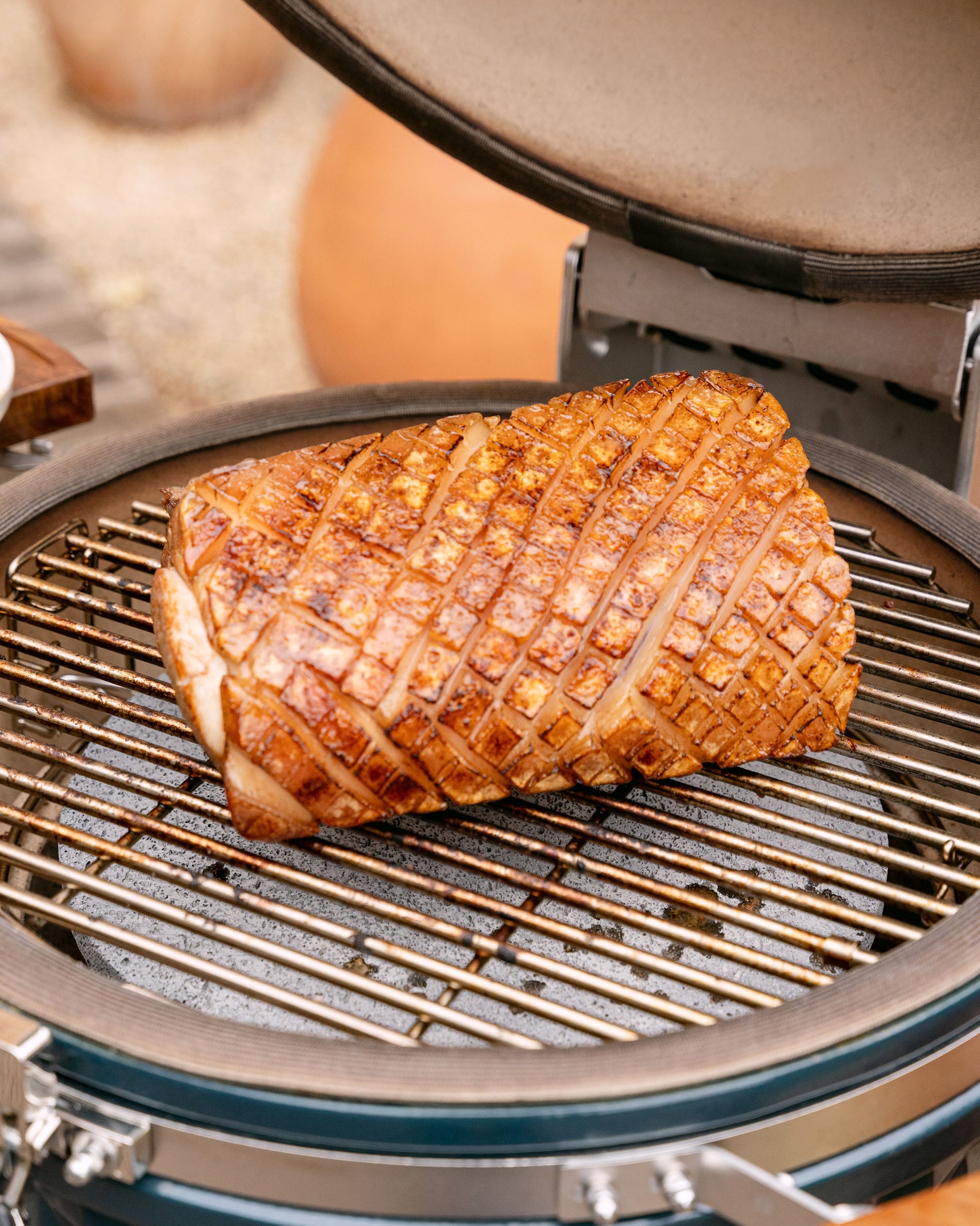 Cuisson d’un rôti de porc sur la grille d’un kamado Kokko, couvercle ouvert, avec une saisie dorée et uniforme.