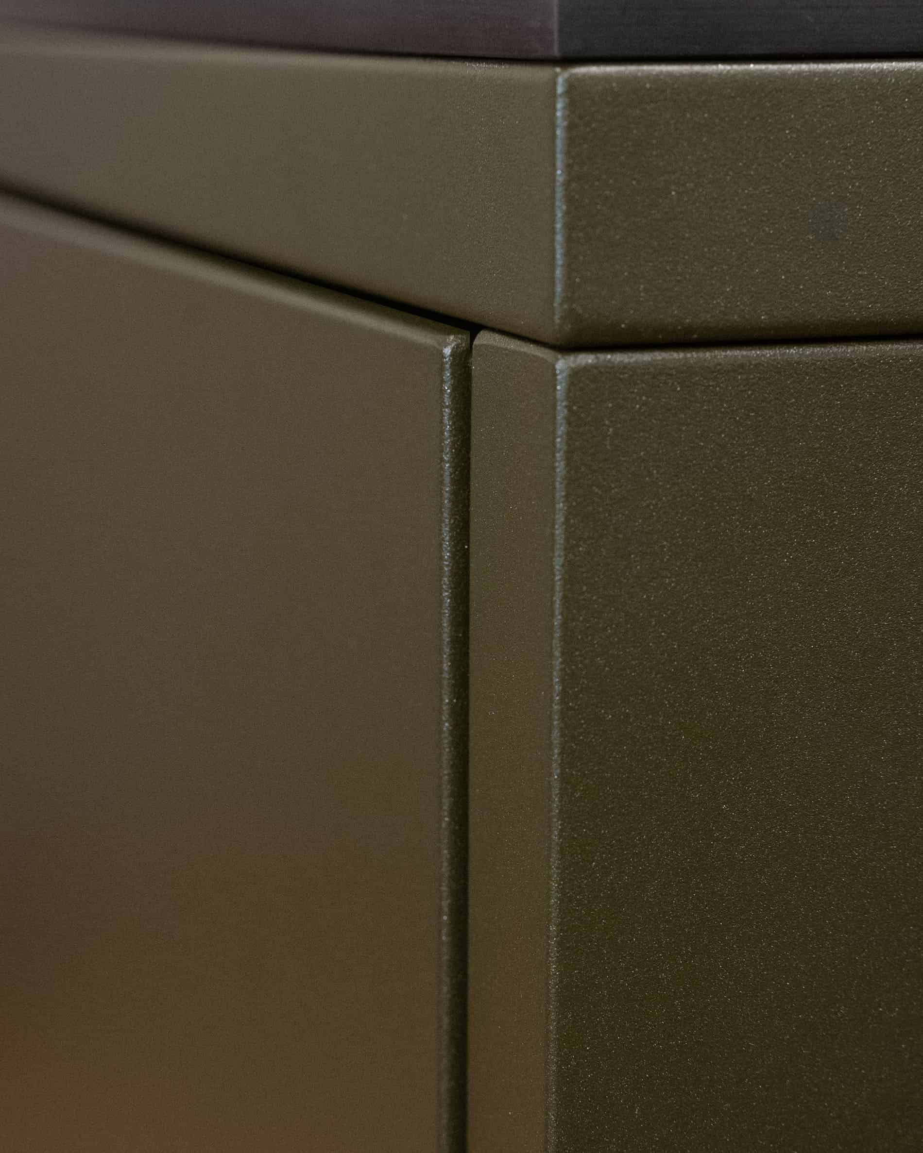 Dettaglio di finitura di una cucina su palafitte, che mostra l’assemblaggio dei pannelli metallici e la texture della facciata color oliva.