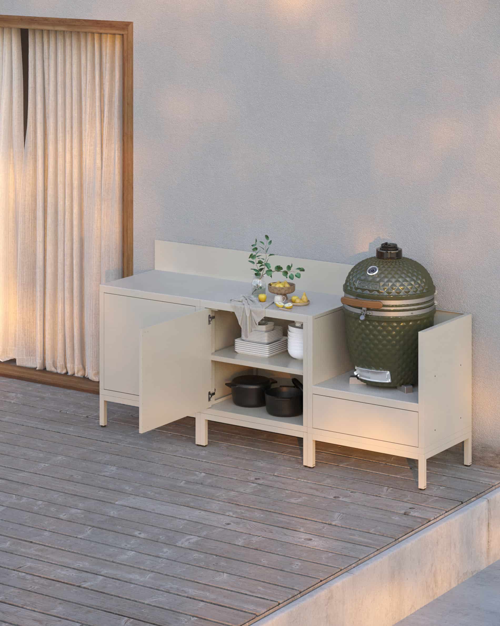 Cucina su palafitte color crema con vani a giorno e chiusi, piano di lavoro chiaro, alzatina coordinata e modulo kamado integrato su struttura rialzata.