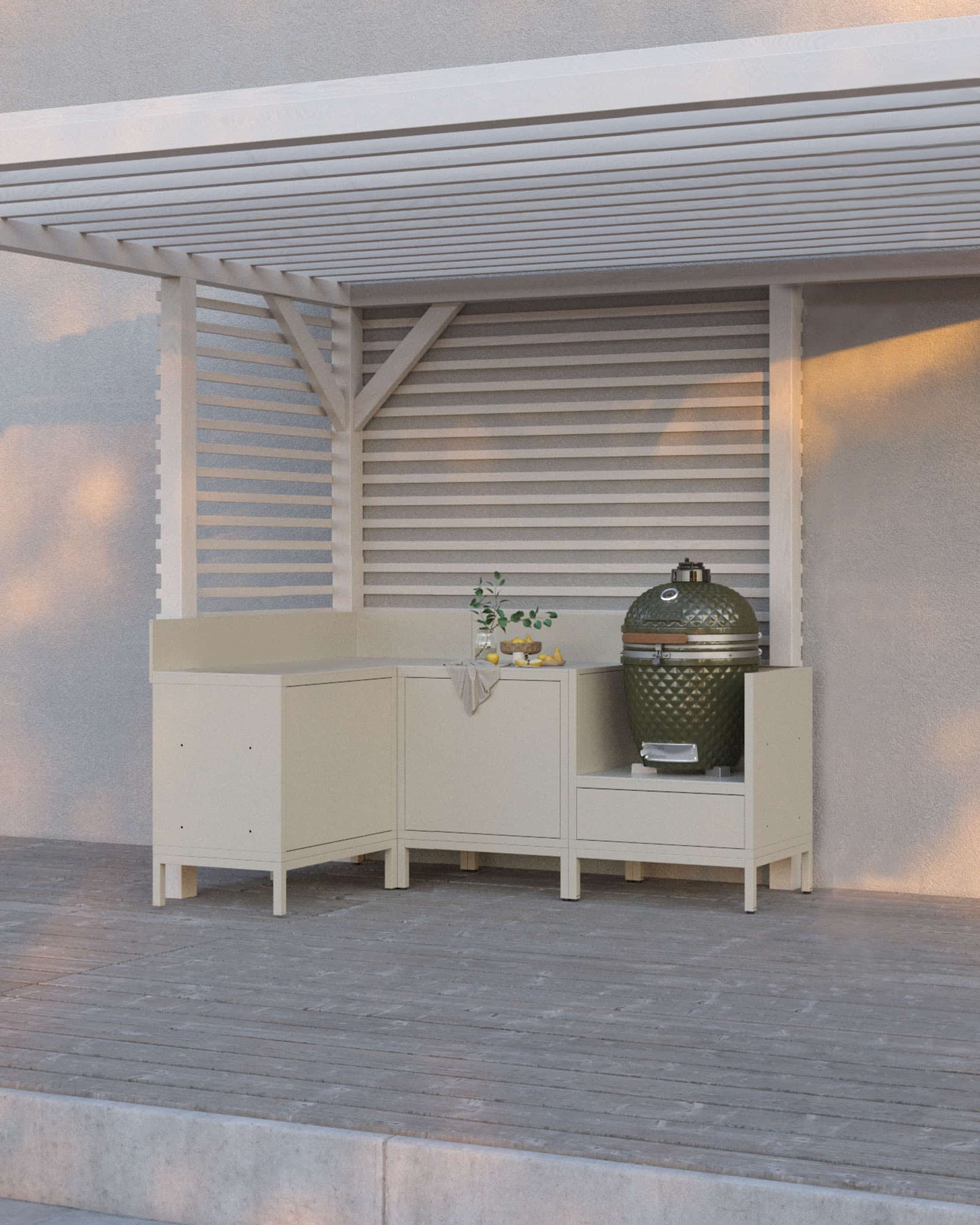 Cucina su palafitte color crema composta da quattro moduli con angolo, piano di lavoro continuo e spazio dedicato al kamado, installata sotto una pergola bianca su terrazza in legno.