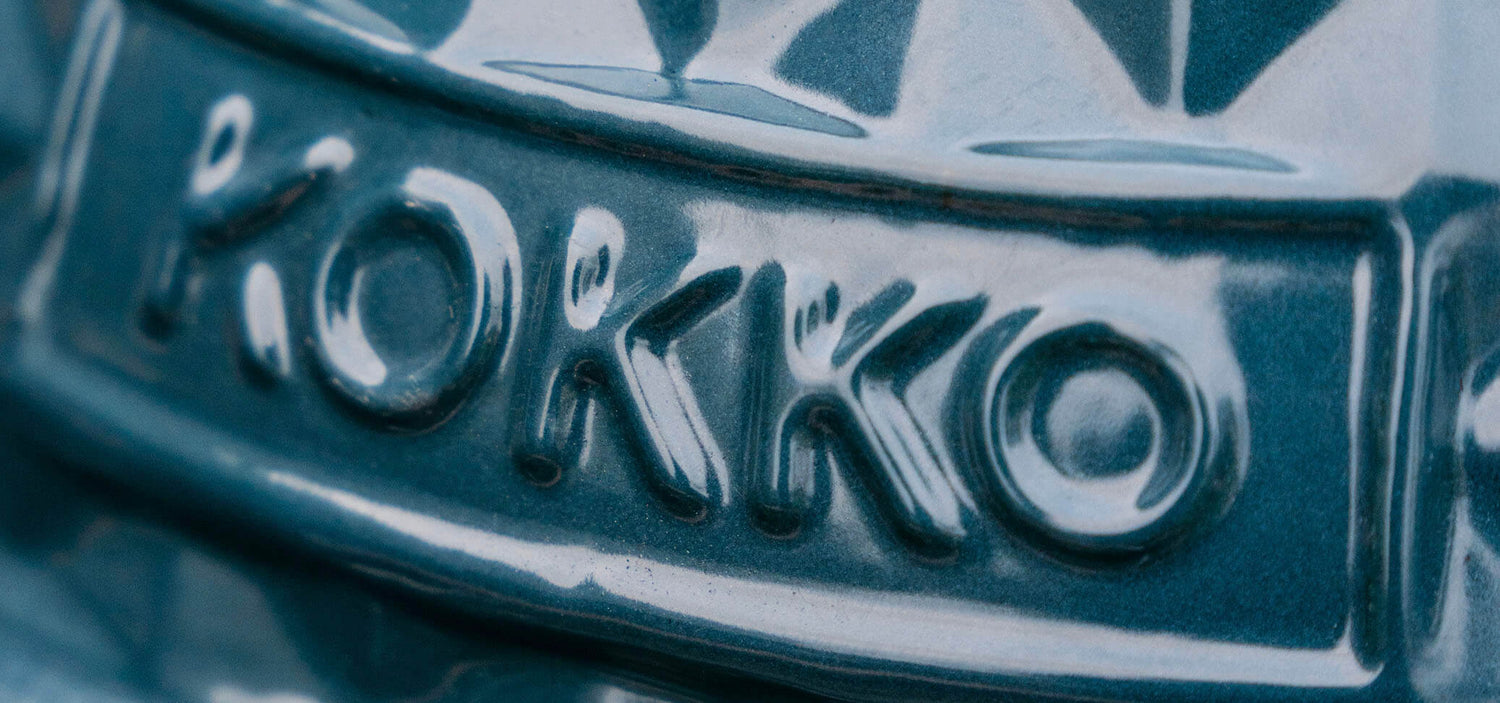 Dettaglio ravvicinato del logo Kokko inciso sulla ceramica smaltata verde petrolio del kamado.