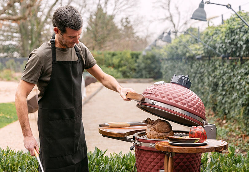 Cottura di un arrosto in un kamado Kokko rosso, con apertura del coperchio e manipolazione degli alimenti all’aperto.